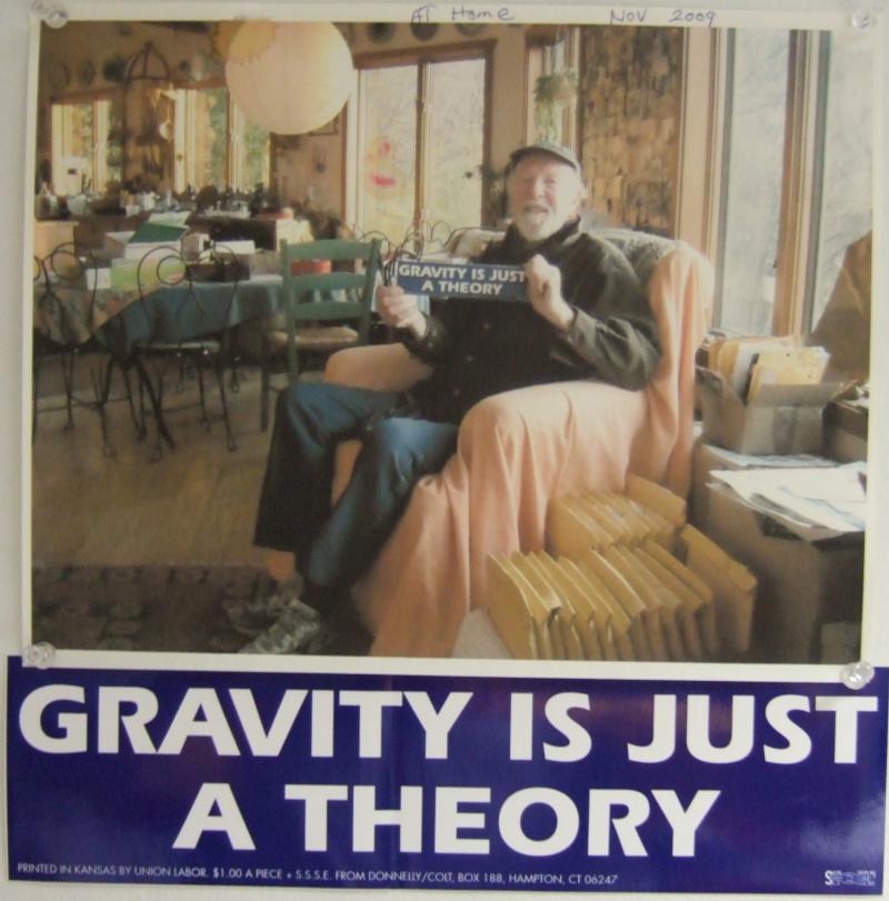Pete Seeger holding his "Gravity is just a theory" bumper sticker